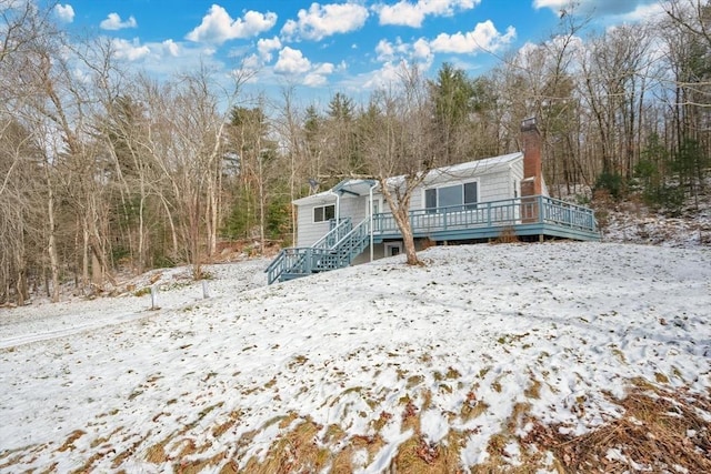 snow covered rear of property featuring a wooden deck