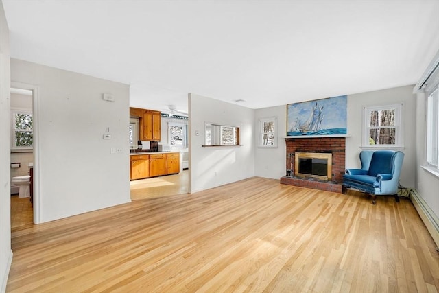 living room with a fireplace, light hardwood / wood-style floors, and a baseboard radiator