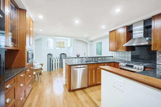44 Dartmouth St Unit 1, Boston, MA 02116 - kitchen featuring a peninsula, wall chimney exhaust hood, arched walkways, a sink, and stainless steel appliances