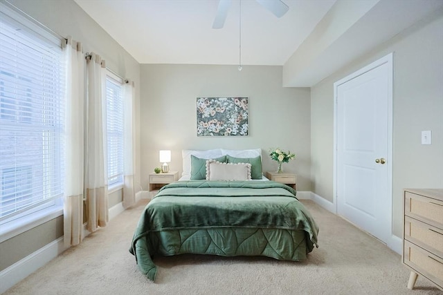 bedroom featuring ceiling fan, light colored carpet, and multiple windows