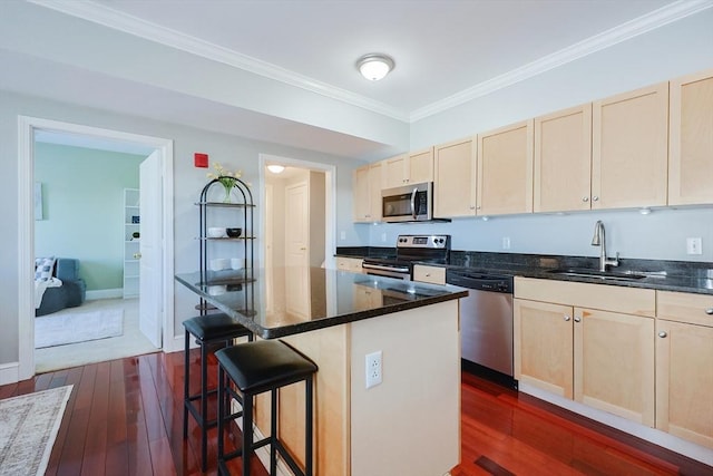 kitchen featuring a kitchen bar, stainless steel appliances, a center island, crown molding, and sink