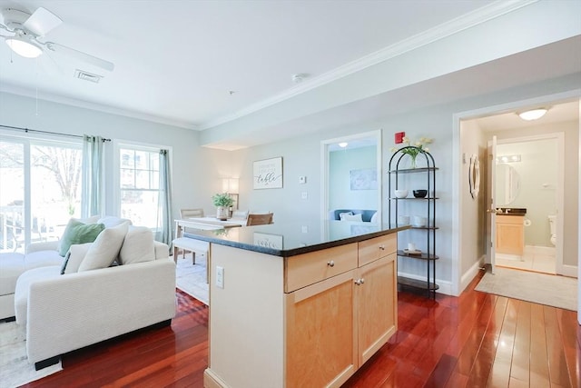 kitchen with ceiling fan, dark hardwood / wood-style floors, light brown cabinets, ornamental molding, and a center island