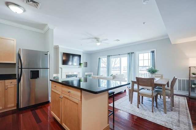 kitchen featuring ceiling fan, a kitchen island, a kitchen breakfast bar, stainless steel fridge with ice dispenser, and ornamental molding