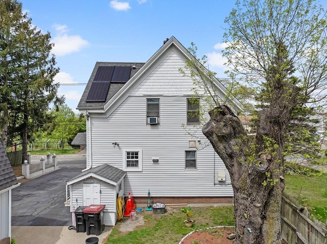 209 Grove St, Brockton, MA 02302 - rear view of property featuring solar panels, a fenced backyard, a shingled roof, and a shed
