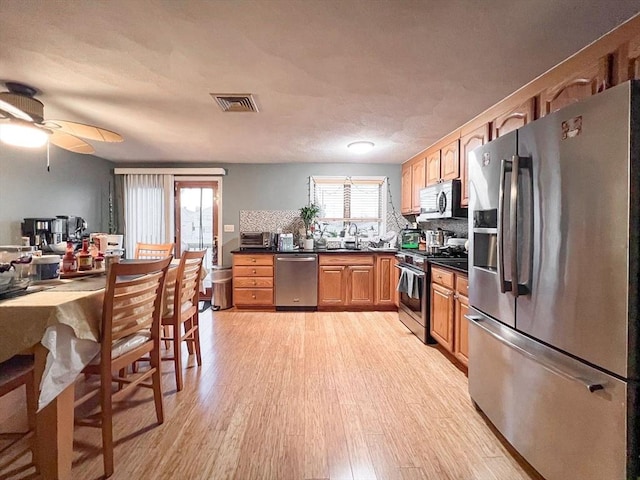 kitchen featuring sink, decorative backsplash, ceiling fan, light hardwood / wood-style floors, and stainless steel appliances