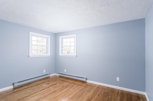 spare room with a textured ceiling, baseboard heating, and light wood-type flooring