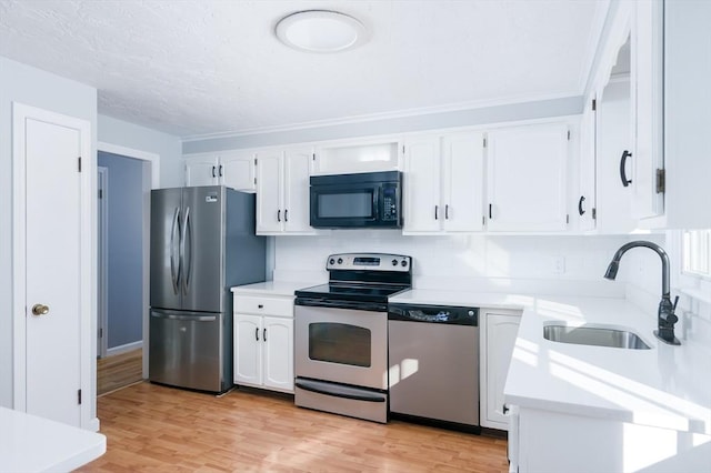 kitchen featuring sink, stainless steel appliances, light hardwood / wood-style floors, and white cabinetry