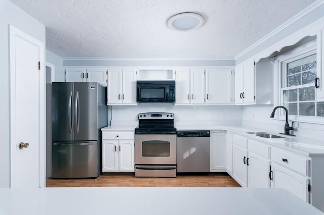 kitchen with a textured ceiling, light hardwood / wood-style floors, white cabinetry, appliances with stainless steel finishes, and sink