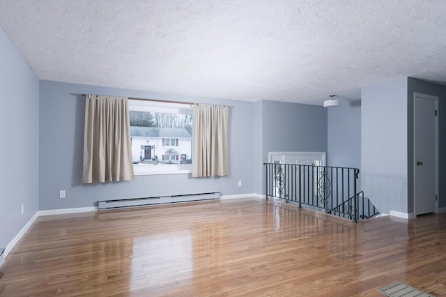 spare room featuring hardwood / wood-style floors, a textured ceiling, and baseboard heating