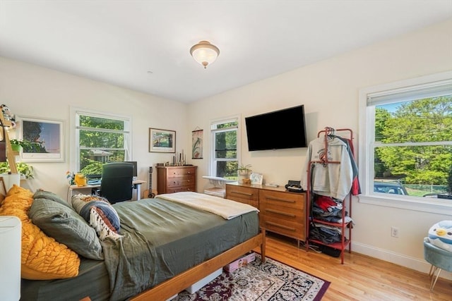 bedroom with light wood-style floors, multiple windows, and baseboards