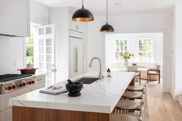 178 Ivy St, Brookline, MA 02446 - kitchen with built in fridge, a sink, an island with sink, stainless steel gas cooktop, and white cabinetry