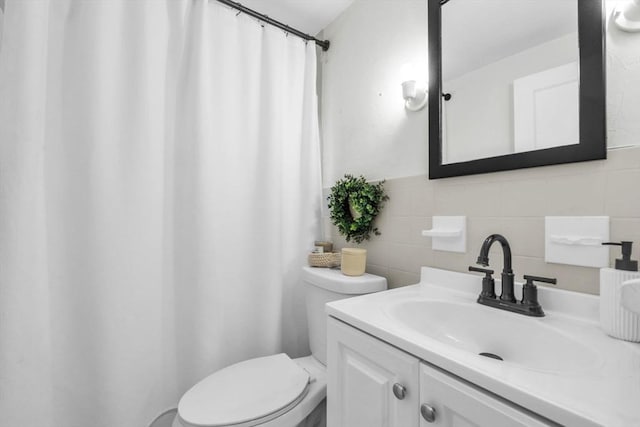 bathroom featuring vanity, tile walls, and toilet