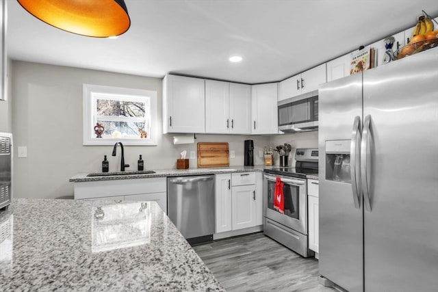 kitchen with white cabinetry, sink, light stone counters, and stainless steel appliances