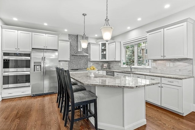 4 Fairfield Pl, Winchester, MA 01890 - kitchen featuring appliances with stainless steel finishes, wall chimney exhaust hood, a kitchen island, decorative backsplash, and recessed lighting