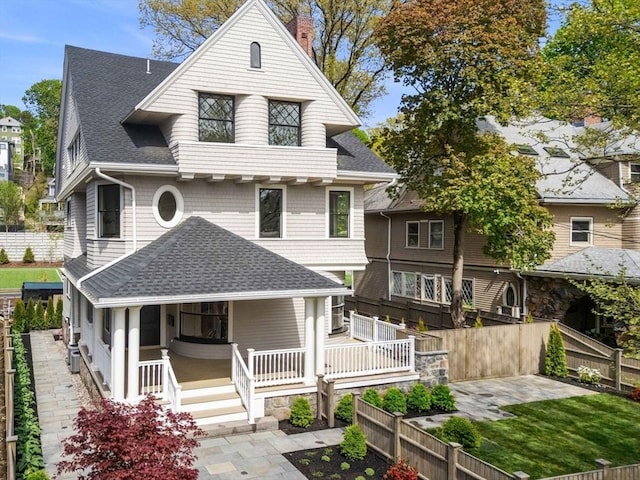 victorian house featuring a porch, a patio, a shingled roof, and fence private yard