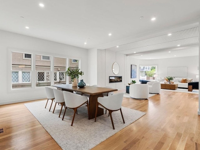 dining space with baseboards, a fireplace, light wood-style flooring, and recessed lighting