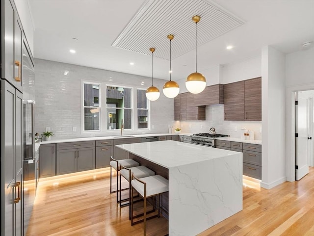 kitchen with a sink, light wood-type flooring, decorative backsplash, and a kitchen island