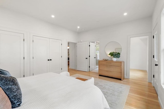 bedroom featuring light wood-type flooring, multiple closets, and recessed lighting