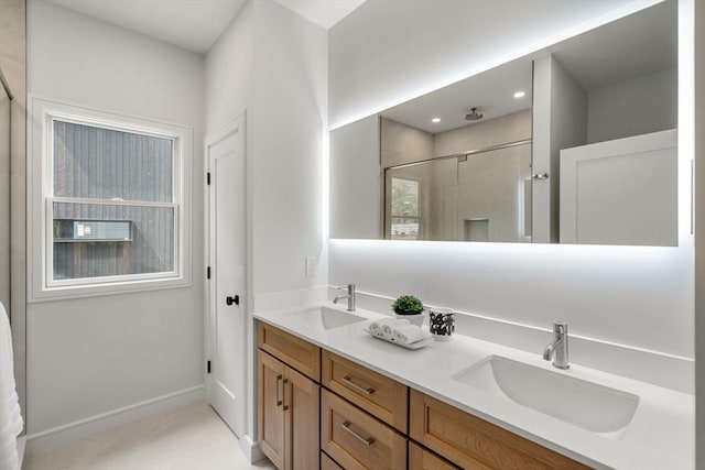 full bath featuring a sink, double vanity, a stall shower, and baseboards