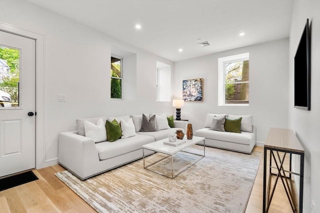 living room featuring recessed lighting, a wealth of natural light, visible vents, and light wood-type flooring