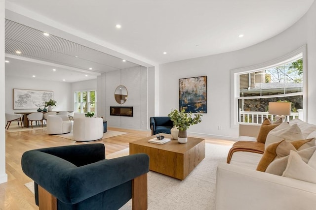living room with baseboards, light wood-style floors, recessed lighting, and a large fireplace