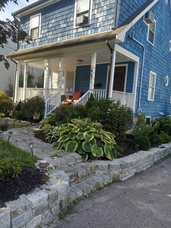 view of front facade with an AC wall unit and covered porch