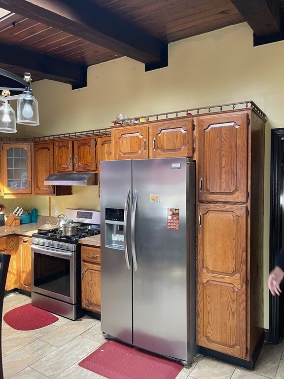 kitchen featuring beam ceiling, appliances with stainless steel finishes, light tile patterned floors, and wood ceiling