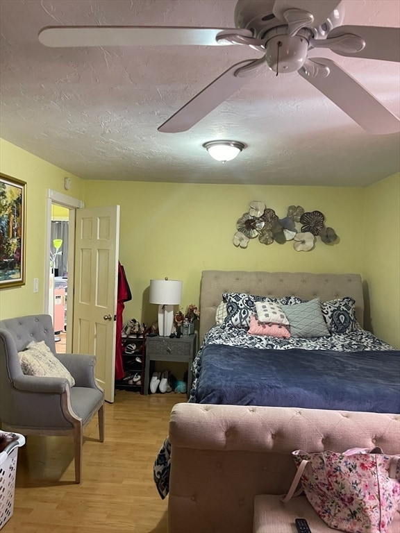 bedroom featuring a textured ceiling, light wood-type flooring, and ceiling fan