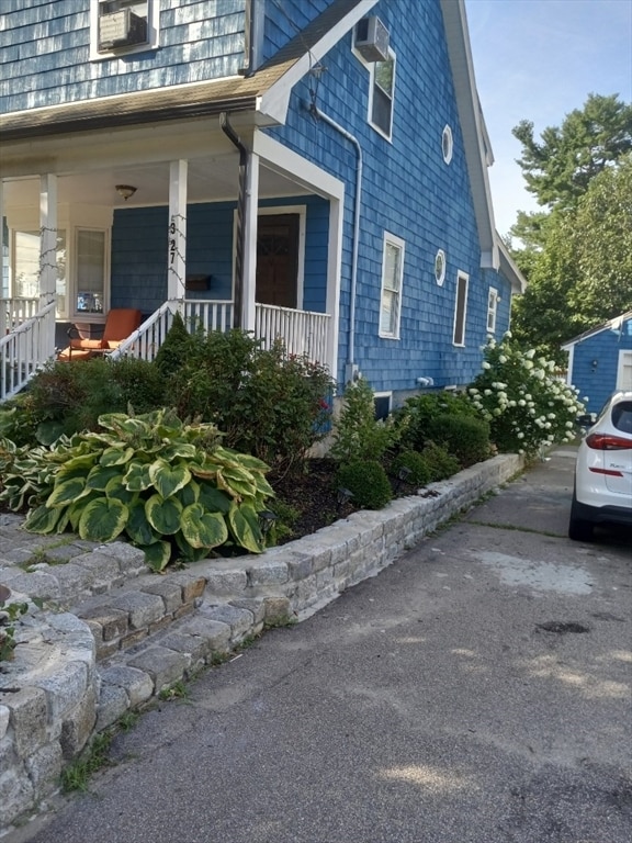 view of side of property with a porch and a wall unit AC