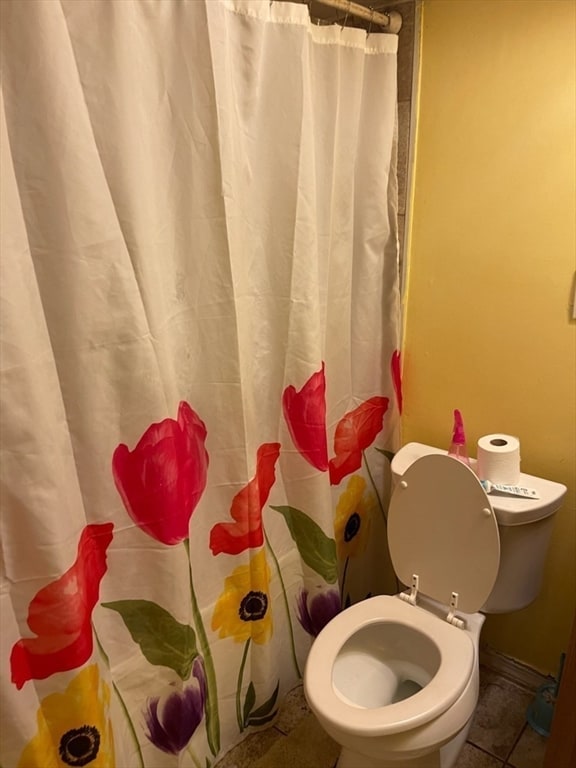 bathroom featuring tile patterned floors, a shower with shower curtain, and toilet