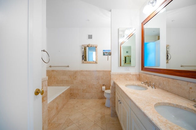 bathroom with tile walls, a bath, tile patterned floors, vanity, and toilet