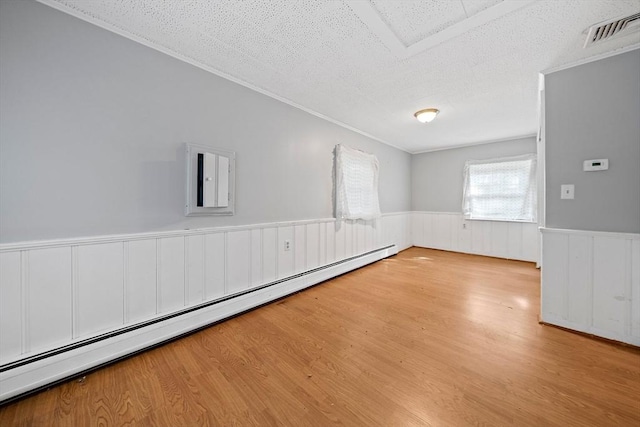 32 Standish Ave, Plymouth, MA 02360 - empty room with a baseboard heating unit, a wainscoted wall, a textured ceiling, wood finished floors, and ornamental molding