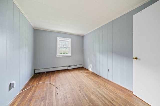 32 Standish Ave, Plymouth, MA 02360 - empty room featuring a baseboard heating unit, wood-type flooring, wood walls, and ornamental molding