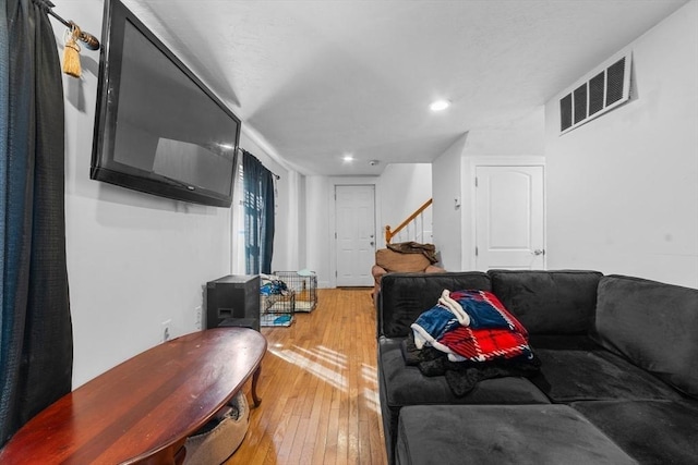 living room featuring light wood-style floors, recessed lighting, visible vents, and stairs