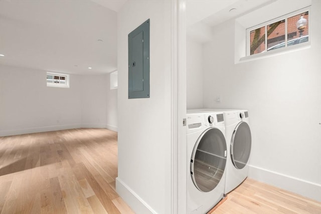 laundry area with laundry area, washer and clothes dryer, electric panel, and light wood-style floors