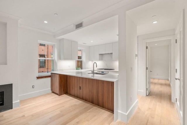 kitchen with a fireplace, light countertops, visible vents, white cabinets, and light wood-type flooring