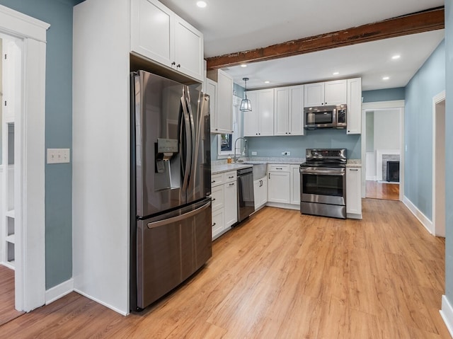 kitchen featuring light hardwood / wood-style floors, white cabinets, hanging light fixtures, and appliances with stainless steel finishes