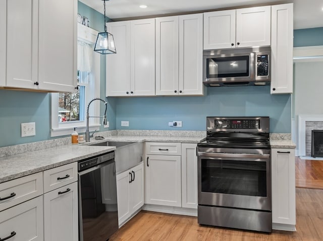 kitchen with white cabinets, light wood-type flooring, and stainless steel appliances