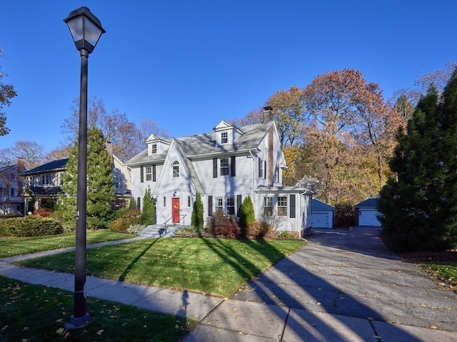 view of front of house featuring an outbuilding, a garage, and a front lawn