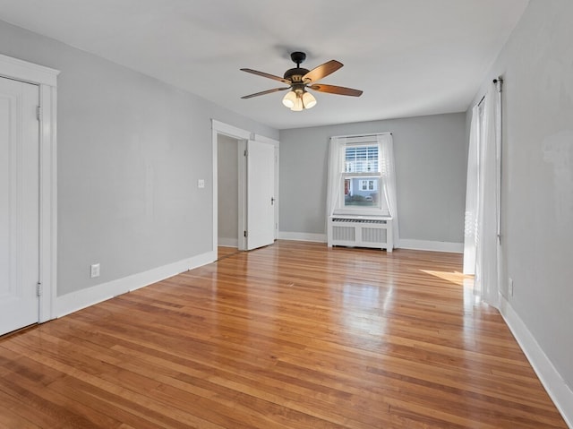 unfurnished room featuring radiator heating unit, light wood-type flooring, and ceiling fan