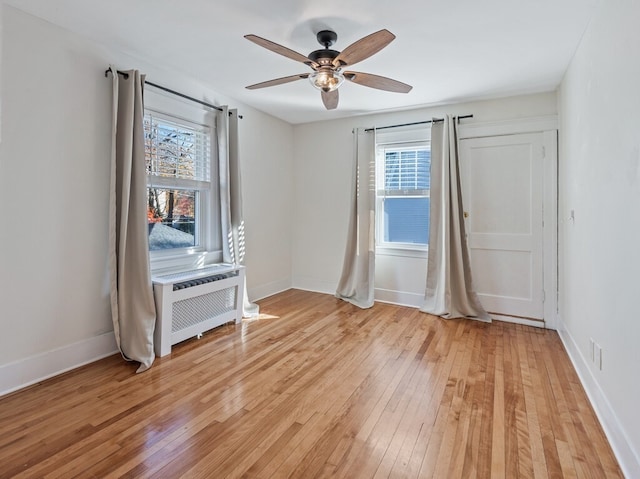 empty room featuring ceiling fan, light wood-type flooring, and a wealth of natural light