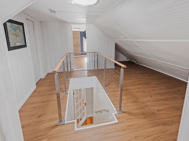 bonus room with wooden walls, hardwood / wood-style floors, and lofted ceiling