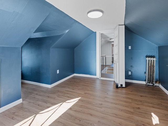 bonus room with light hardwood / wood-style flooring, radiator, and lofted ceiling