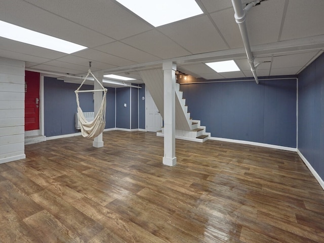 basement with dark hardwood / wood-style flooring and a paneled ceiling