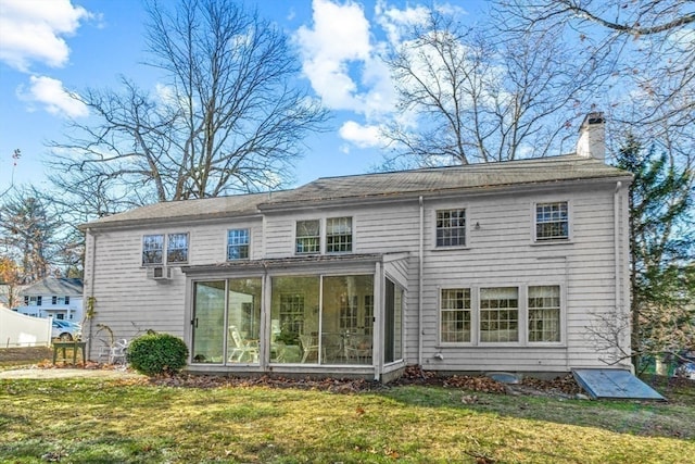 back of property featuring a sunroom and a lawn