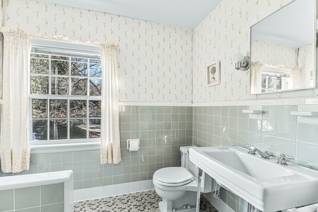 bathroom with a wealth of natural light, tile walls, and toilet