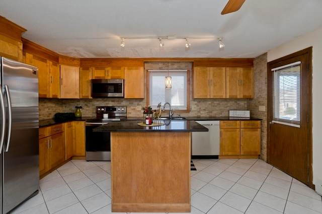 kitchen with sink, light tile patterned floors, tasteful backsplash, a kitchen island, and stainless steel appliances