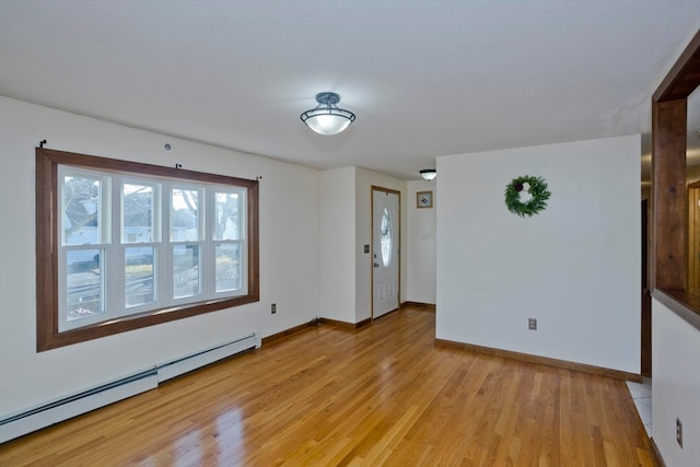 empty room with baseboard heating and light hardwood / wood-style flooring