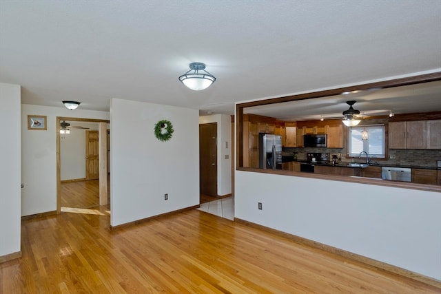 kitchen with decorative backsplash, light wood-type flooring, a textured ceiling, stainless steel appliances, and sink