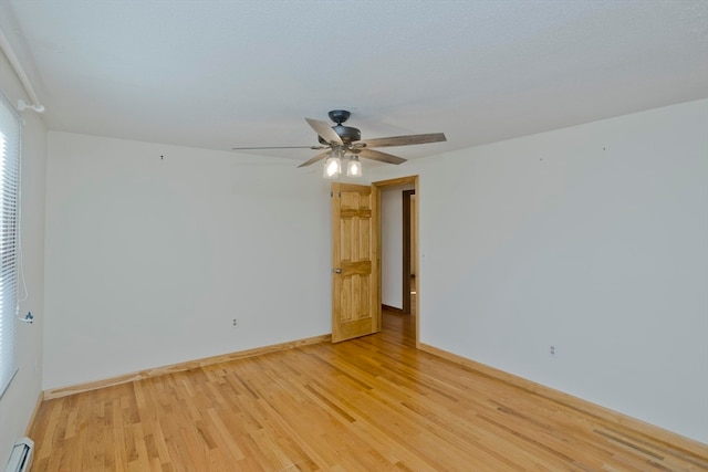 empty room with light hardwood / wood-style floors, a baseboard radiator, and ceiling fan